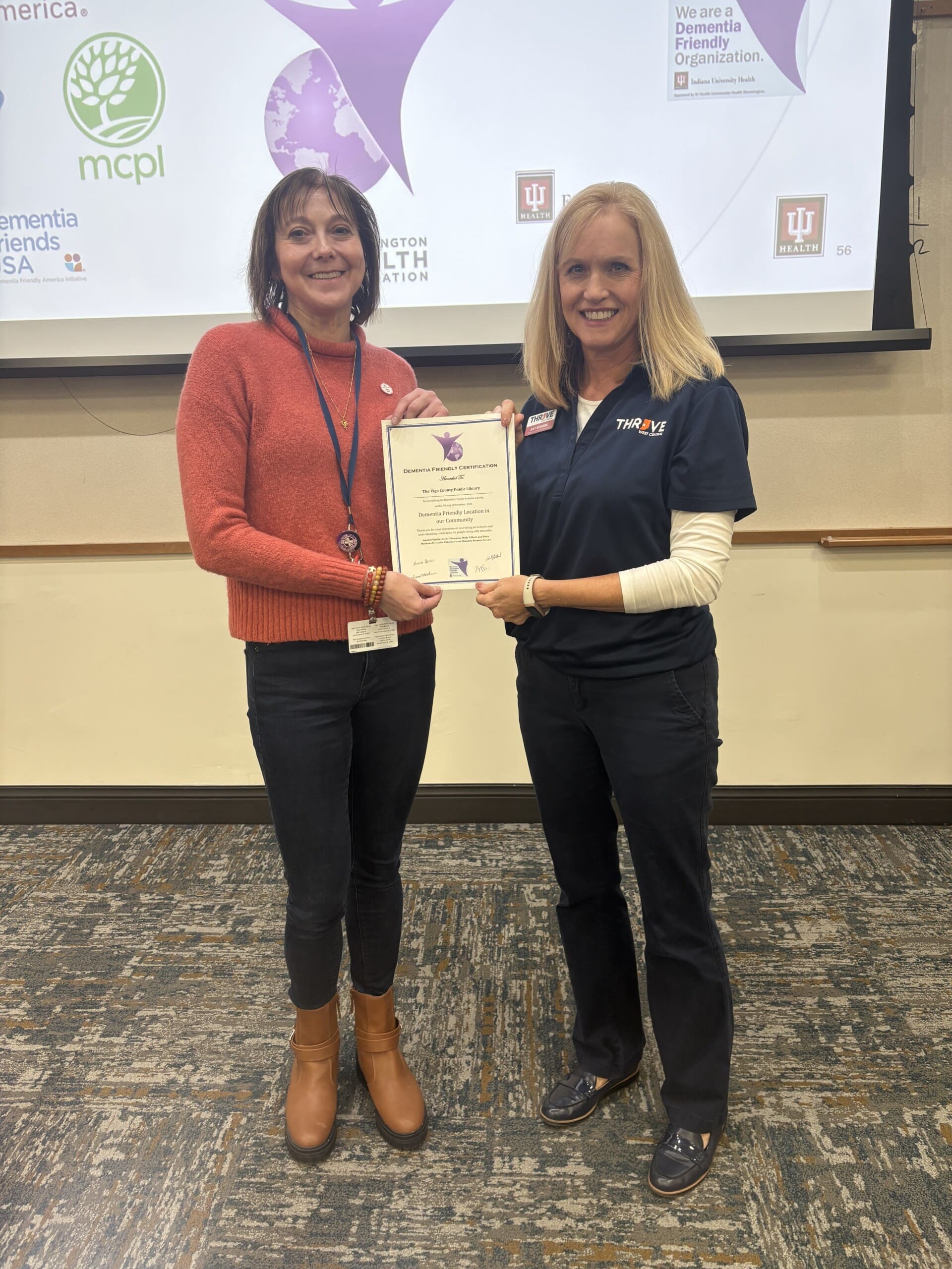 Two women hold certificate between them.